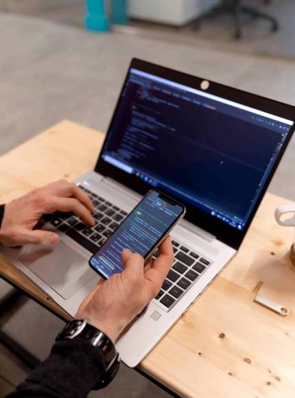 Laptop und Smartphone zeigen Programmiercode, genutzt in einer Webdesign Agentur